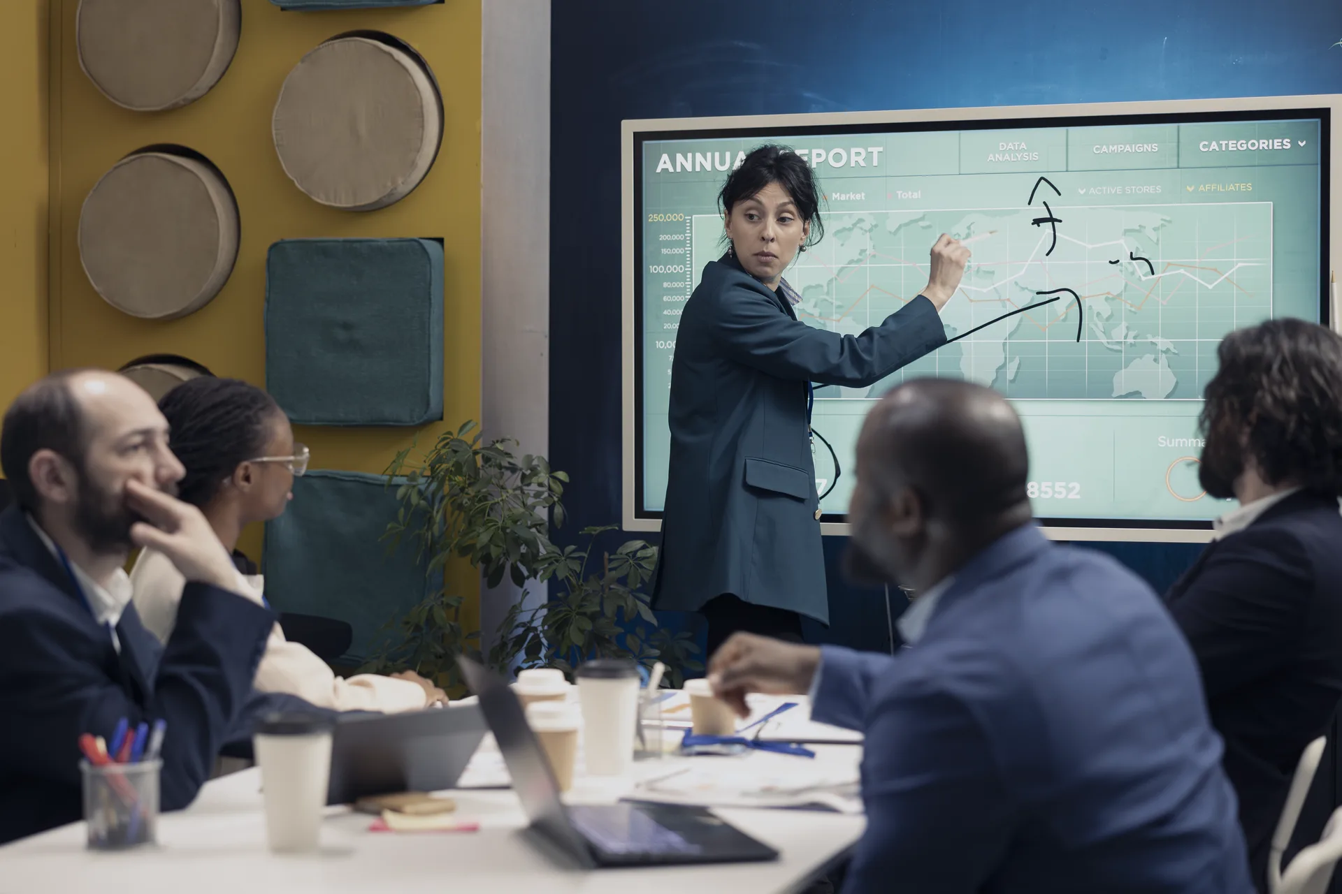 Executive presenting annual business report data on a large screen to a seated team